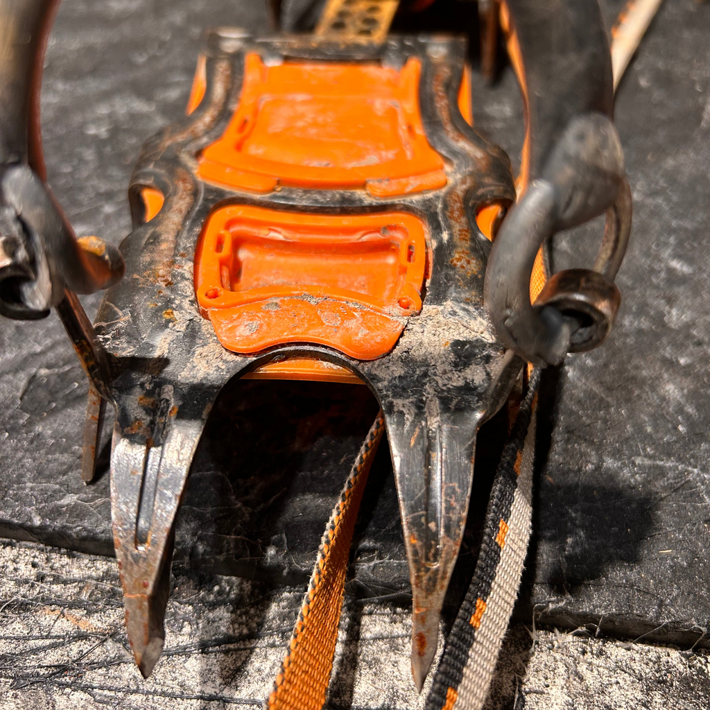 Service d'affûtage de crampons d'alpinisme 4c+ montrant des pointes métalliques usées et une structure orange