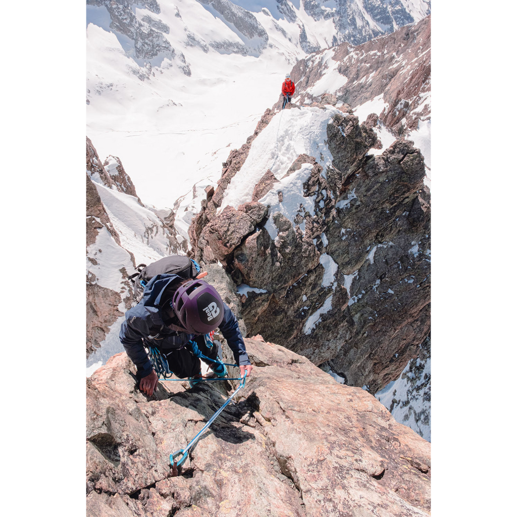 Alpiniste utilisant une sangle extensible 4c+ Beal Alpi 60cm sur une paroi rocheuse enneigée en haute montagne