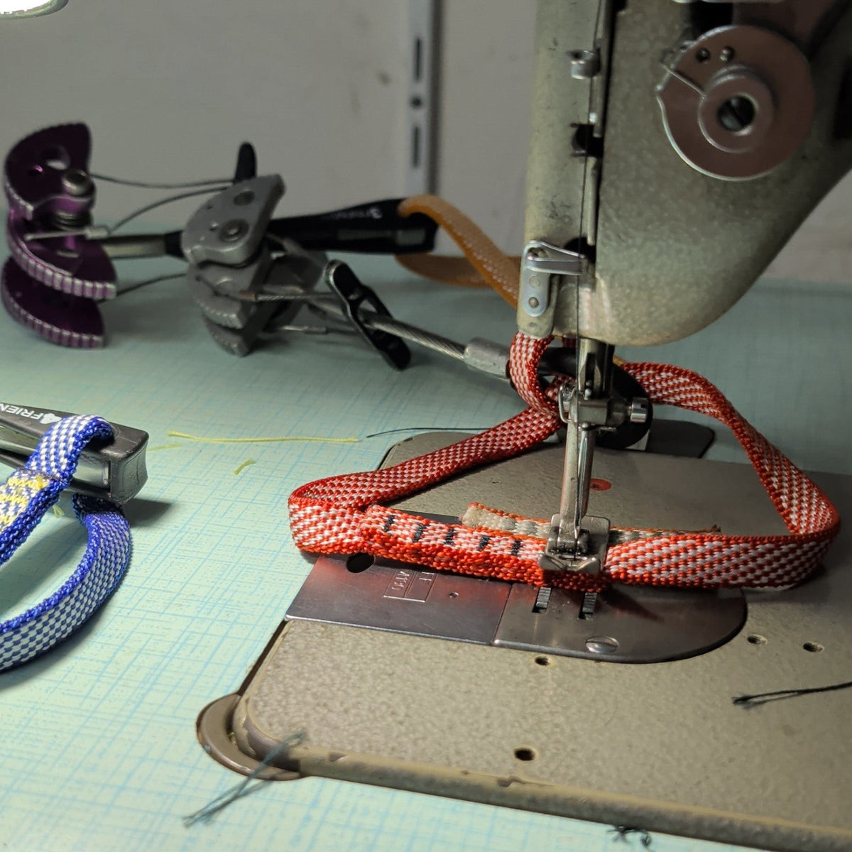 Servicio de ressanglage de friends 4c+ con costura de seguridad en cinta de Dyneema roja sobre máquina de coser
