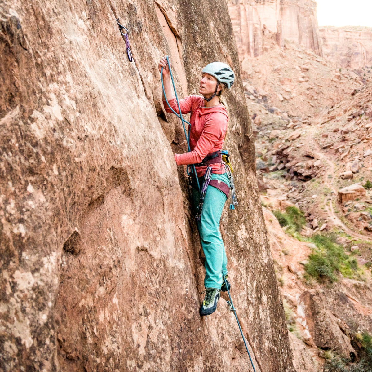 Escaladora con arnés 4c+ Cuesta Femme en una pared de roca, diseñado para la morfología femenina con ajuste ergonómico.