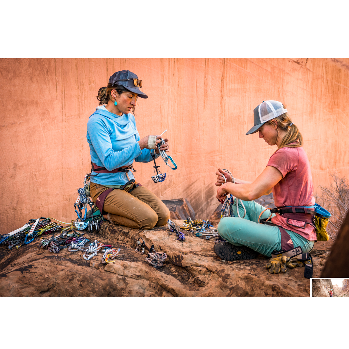 Dos escaladoras con arneses 4c+ Cuesta Femme organizando equipo de escalada en un entorno rocoso al aire libre.